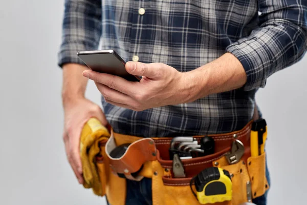 Работник или строитель с телефоном и рабочими инструментами — стоковое фото