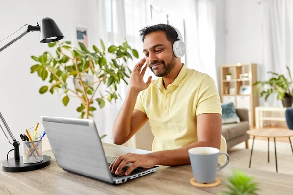 Hombre en auriculares con portátil trabajando en casa — Foto de Stock