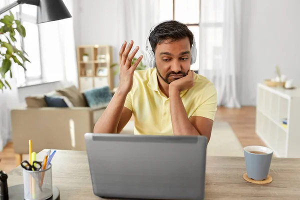 Pria dengan headphone dengan laptop yang bekerja di rumah — Stok Foto