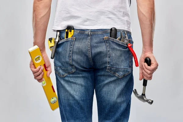 Homme avec niveau et outils de travail dans les poches Photo De Stock