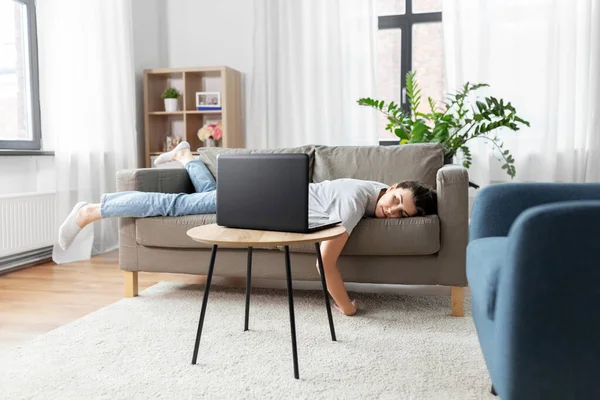 Скучающая женщина с ноутбуком, лежащим дома на диване — стоковое фото