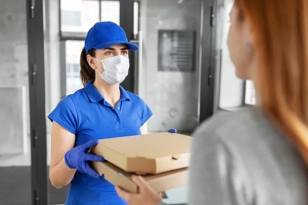 Entrega chica en la máscara dando cajas de pizza a la mujer — Foto de Stock