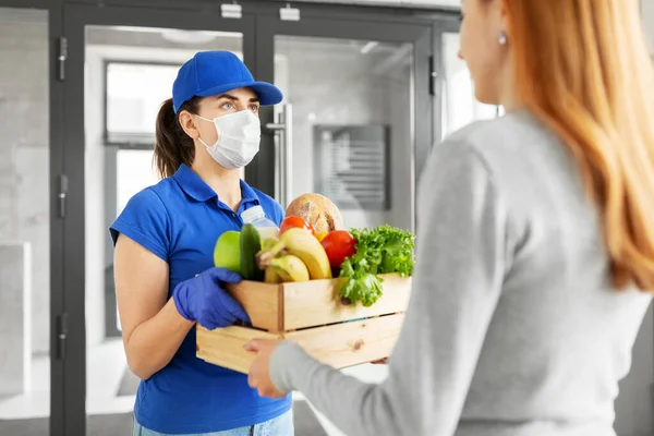 Entrega chica en la máscara dando caja de comida a la mujer —  Fotos de Stock