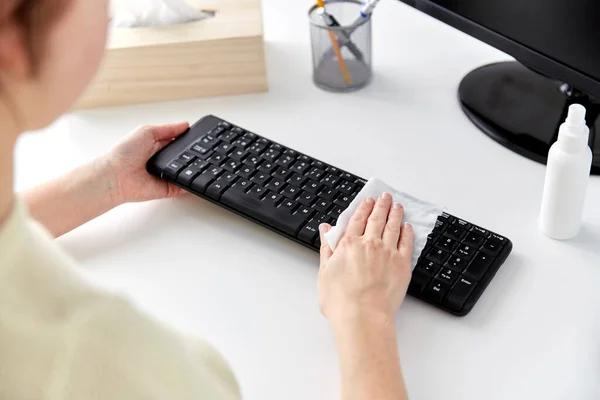 close up of woman cleaning keyboard with tissue