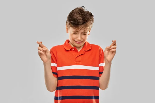 Menino em vermelho polo t-shirt segurando dedos cruzados — Fotografia de Stock