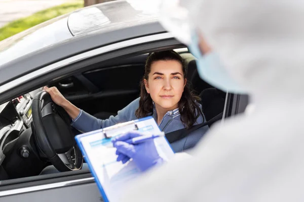 클립보드를 하고 있고 차를 타고 있는 여성 의료 종사자 — 스톡 사진