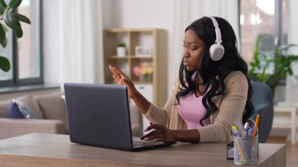 Mujer en auriculares con portátil trabajando en casa — Vídeo de stock