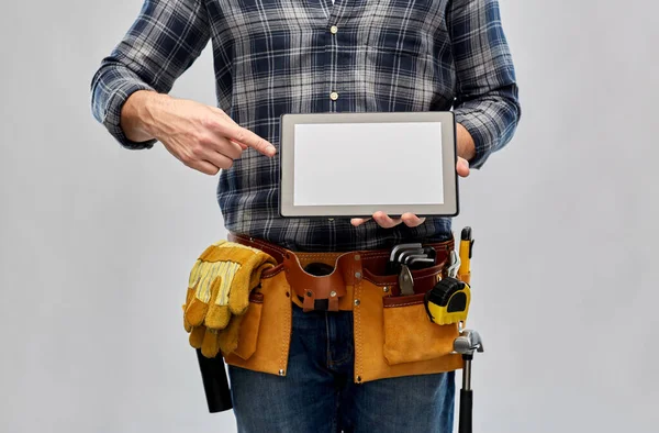 Мужчина строитель с рабочими инструментами, показывающими планшетный компьютер — стоковое фото