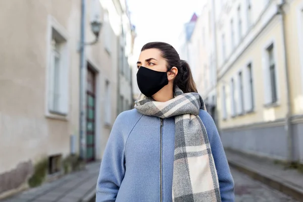 Nainen yllään suojaava uudelleenkäytettävä naamio kaupungissa — kuvapankkivalokuva