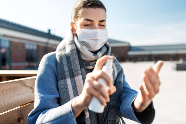 Woman in mask spraying hand sanitizer outdoors — Stock Photo, Image