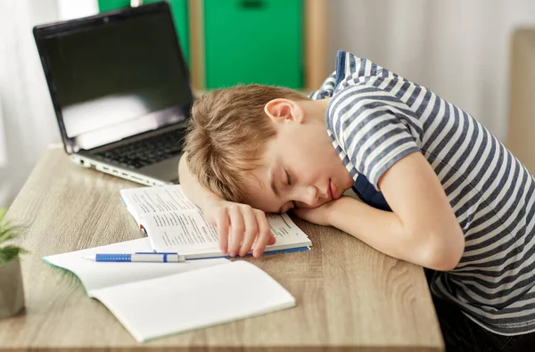 Yorgun öğrenci çocuk evde masa başında uyuyor. — Stok fotoğraf
