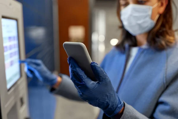 Mulher em máscara com smartphone na máquina de pacote — Fotografia de Stock