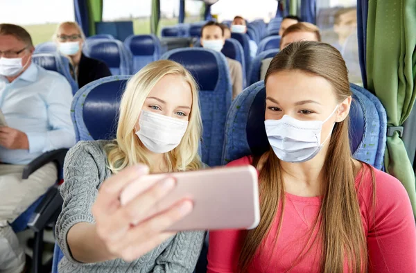 Женщины в медицинских масках делают селфи в туристическом автобусе — стоковое фото