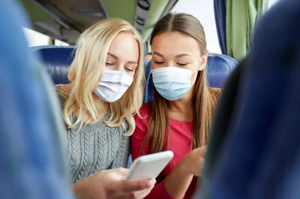 Женщины в масках в туристическом автобусе со смартфоном — стоковое фото