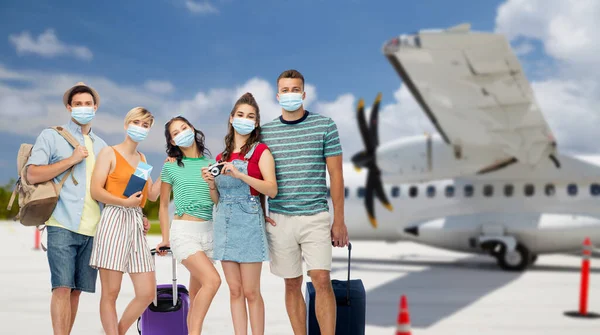 Друзья в масках с дорожными сумками на самолете — стоковое фото