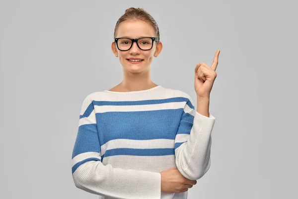 Heureux adolescent fille dans lunettes pointant doigt vers le haut — Photo