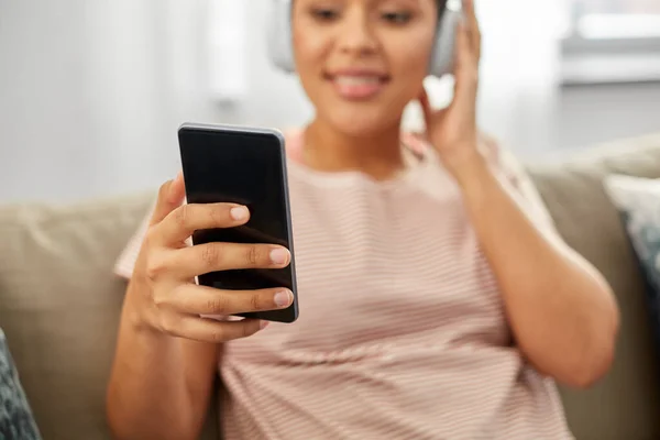 Vrouw met smartphone luisteren naar muziek thuis — Stockfoto