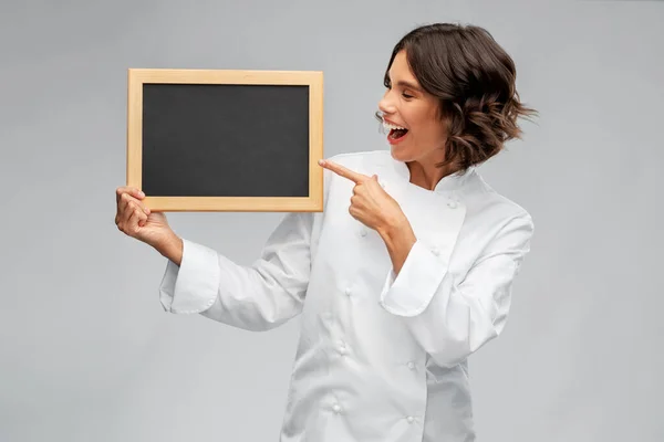 Usmívající se kuchařka drží černou tabuli — Stock fotografie