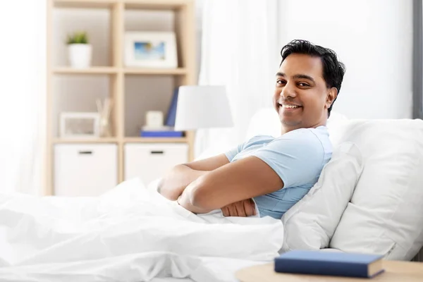 Felice uomo indiano sorridente sdraiato a letto a casa — Foto Stock