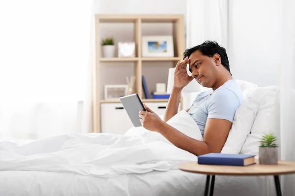 Benadrukt indiase man met tablet pc in bed thuis — Stockfoto