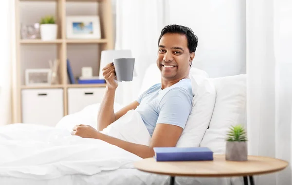 Šťastný indián muž pije kávu v posteli doma — Stock fotografie