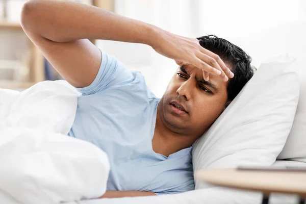 Indiaanse man met hoofdpijn liggend in bed thuis — Stockfoto