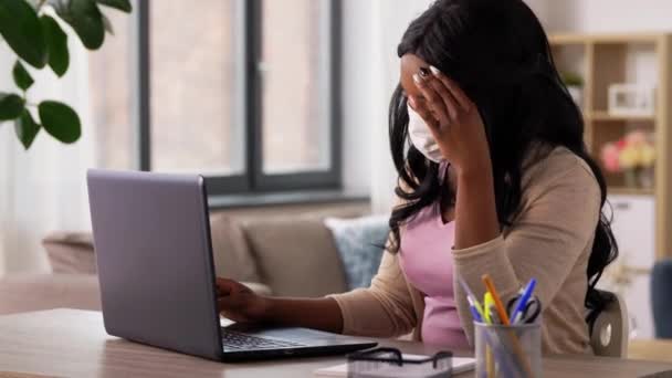 Женщина в маске с ноутбуком работает в домашнем офисе — стоковое видео
