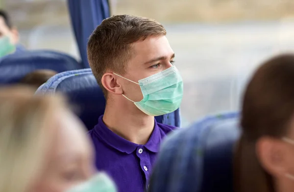 Fiatal férfi orvosi maszkban ül az utazó buszon — Stock Fotó