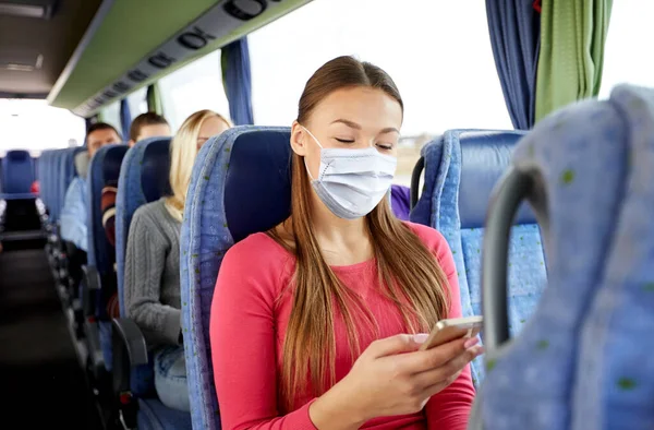 Женщина в маске со смартфоном в автобусе — стоковое фото