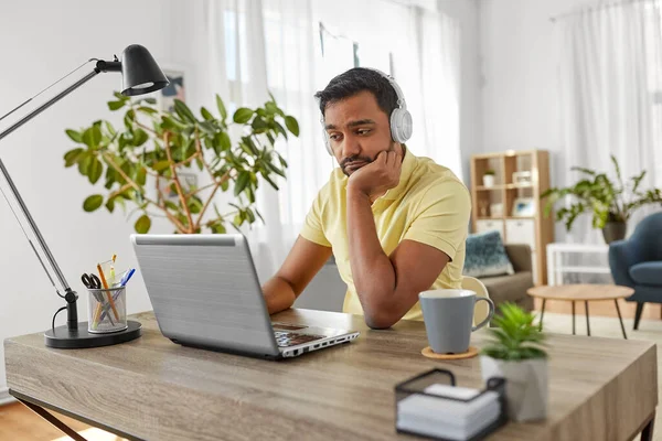 Pria dengan headphone dengan laptop yang bekerja di rumah — Stok Foto