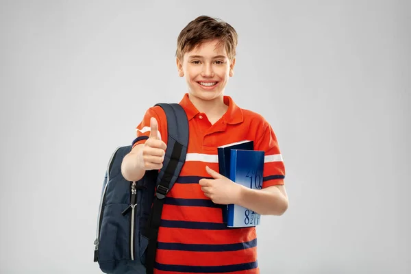 Estudante menino com saco e livros mostrando polegares para cima — Fotografia de Stock