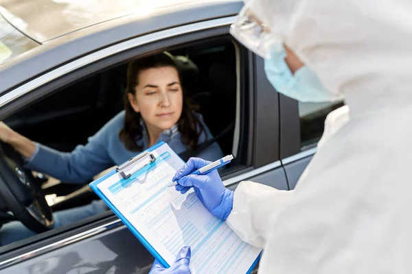 Trabajador sanitario con portapapeles y mujer en coche —  Fotos de Stock