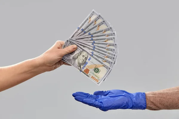 Szoros kéz a kézben orvosi kesztyű ad pénzt — Stock Fotó