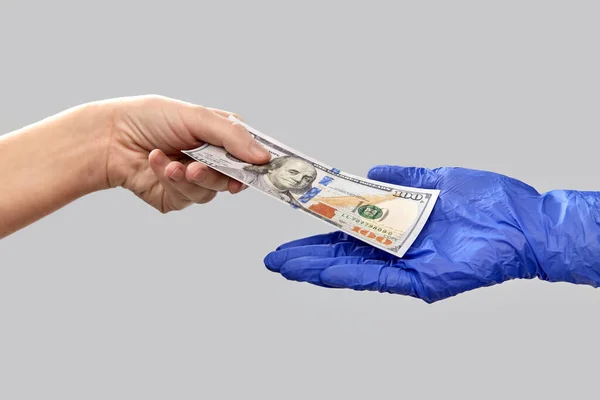 Close-up van de hand in medische handschoen geven geld — Stockfoto