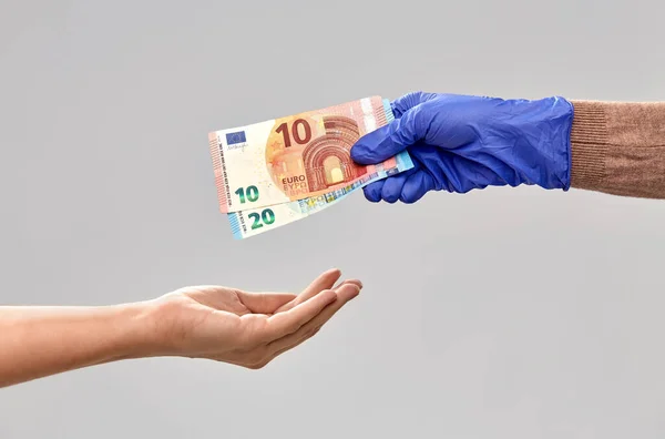 Närbild hand i medicinsk handske ger pengar — Stockfoto