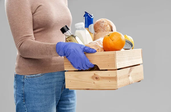 woman in gloves with food in wooden box