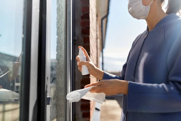 Woman cleaning door handle with disinfectant spray — Stock Photo, Image