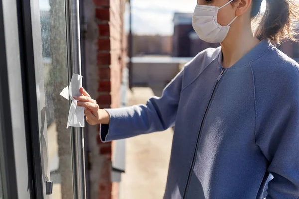 Vrouw in masker reinigen deurkruk met natte veeg — Stockfoto