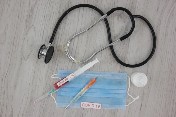 stethoscope with medical mask and vaccine with syringe protecting from coronavirus on wooden table background