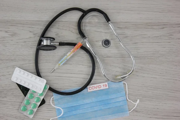 stethoscope with medical mask and vaccine with syringe protecting from coronavirus on wooden table background