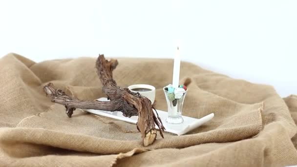 šálek kávy se sušenými klády a svíčkou na dřevěném podstavci stolu