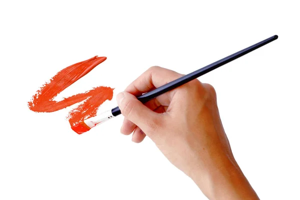 Hand holds the brush with red paint — Stock Photo, Image