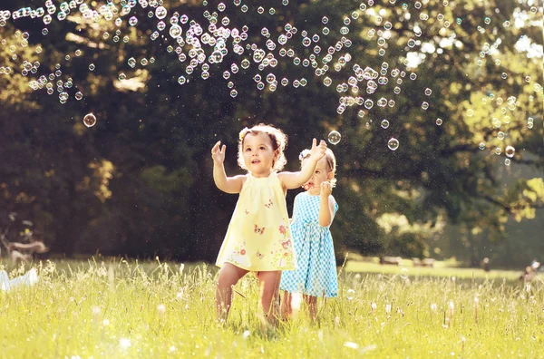 Liten flicka blåser såpbubblor på en sommaräng — Stockfoto