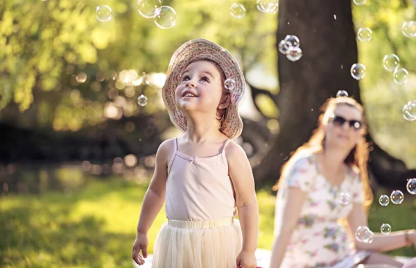 Mother and daughter looking at the soap bubbles — Stock Photo, Image