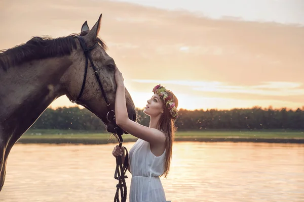 Linda chica rubia acariciando un caballo — Foto de Stock