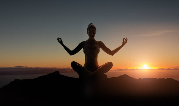 Silhouette of a young meditating woman 