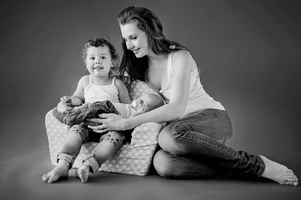 Jovem mãe sentada no chão com seus dois bebês — Fotografia de Stock