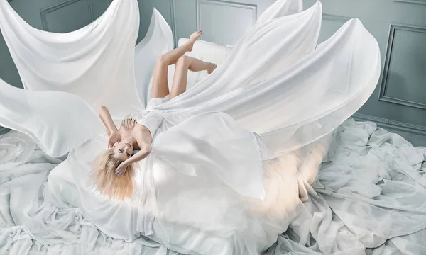 매력적인 금발 여자 순수 화이트 시트에 누워 스톡 사진