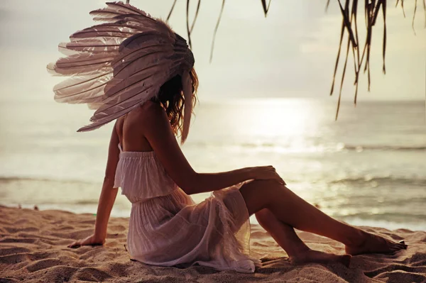 Mulher loira com uma enorme pluma assistindo o pôr do sol — Fotografia de Stock