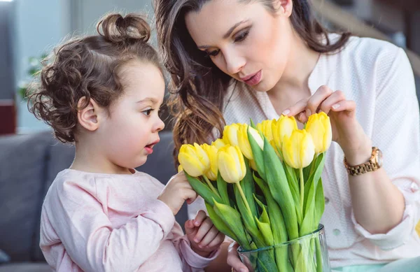 Красивая мать показывает тюльпаны своей дочери — стоковое фото